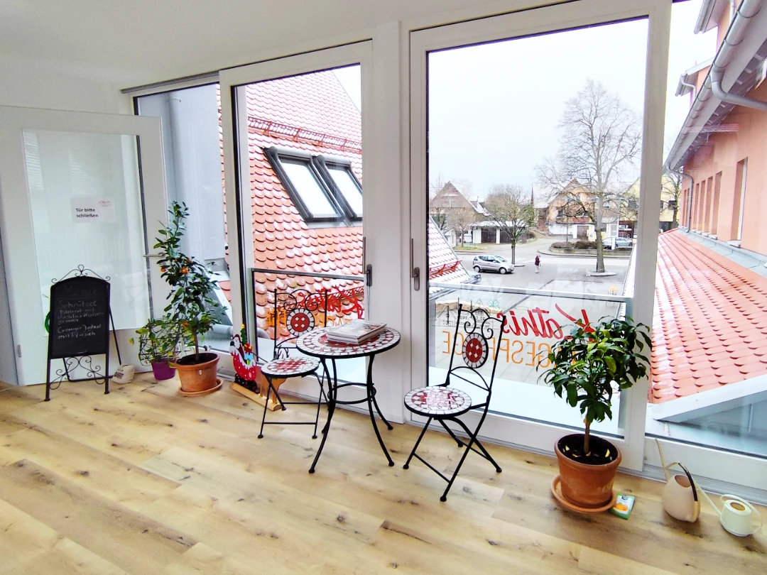 Der lichtdurchflutete Eingangsbereich zu Kathis Begegnungscafe mit großen Fenstern